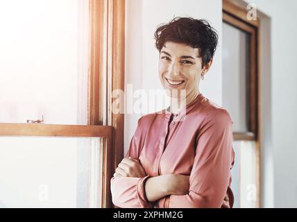 Piccola impresa, donna o sicuro di sé alla finestra per ritratti, professionisti o felici di opportunità. Imprenditrice donna, armi incrociate o sorridere in ufficio Foto Stock