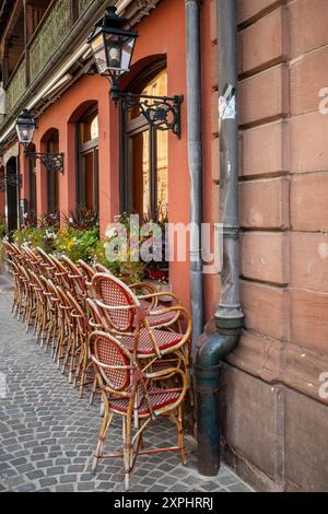 Scena tipica all'esterno di un caffè francese di prima mattina con sedie impilate, fiori all'esterno e lampade ornate. Foto Stock