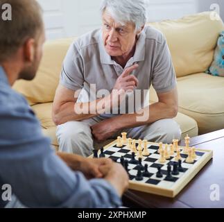 Padre anziano, uomo o insegnante di scacchi in casa per giochi o competizioni con strategia e risoluzione dei problemi. Genitore anziano, lezione e pensione per la sfida Foto Stock