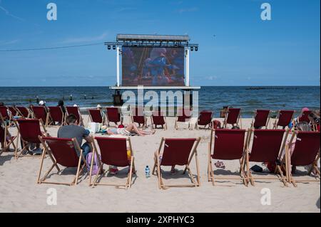 25.07.2024, Heringsdorf, Usedom, Meclemburgo-Vorpommern, Deutschland, Europa - Urlauber sitzen im Kaiserbad Heringsdorf am Strand und schauen einen Film im Open-Air-Kino auf der beliebten deutschen Urlaubsinsel an der Ostsee. *** 25 07 2024, Heringsdorf, Usedom, Meclemburgo-Vorpommern, Germania, i turisti europei si siedono sulla spiaggia nel resort imperiale di Heringsdorf e guardano un film al cinema all'aperto sulla popolare isola di vacanza tedesca sul Mar Baltico Foto Stock