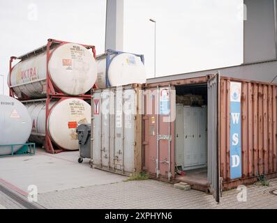 Contenitori e grandi serbatoi cilindrici in un terminal di spedizione a Lipsia. Questa immagine ritrae la natura industriale della logistica e dei trasporti, che rappresenta il movimento globale delle merci e delle infrastrutture moderne. Foto Stock