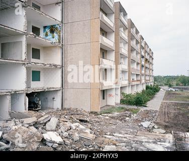 Un edificio Plattenbau abbandonato a Eisenhüttenstadt in fase di demolizione. Detriti visibili e interni esposti, tra cui una stanza con carta da parati tropicale, che riflette il decadimento degli spazi abitativi e dei sogni precedenti. Foto Stock