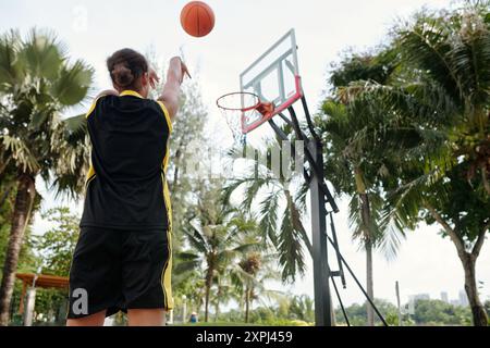 Giocare a pallacanestro sotto le palme nel campo all'aperto Foto Stock