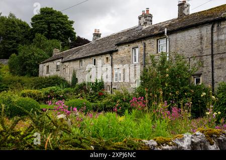 Grassington Yorkshire Regno Unito - 27 luglio 2024. Incantevoli cottage in pietra circondati da giardini lussureggianti e fiori vivaci in una giornata nuvolosa. Foto Stock