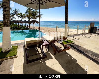 Rilassanti sdraio con ombrelloni in una piscina e spiaggia di un grande hotel di lusso caraibico, con una spiaggia di sabbia fine bianca e dorata con grido Foto Stock