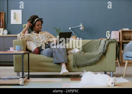Donna che si rilassa sul divano mentre utilizza un notebook Foto Stock
