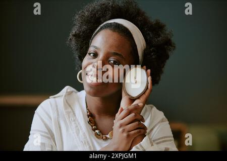 Donna afroamericana sorridente che tiene la candela contro Cheek Foto Stock