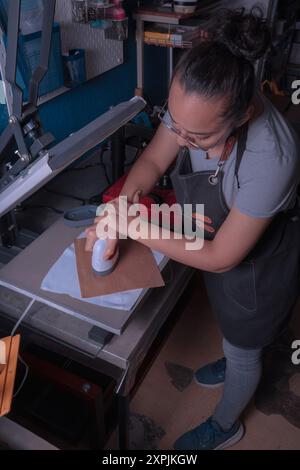 La giovane lavoratrice della sua officina realizza il processo di sublimazione con un'etichetta, una stampa e un concetto di design grafico. Foto Stock