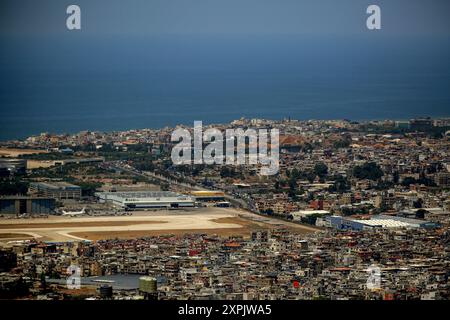 Ain Anoub, Ain Anoub, Libano. 6 agosto 2024. Un aereo siede sull'asfalto dell'aeroporto internazionale di Rafiq Hariri, circondato da case ed edifici del sobborgo meridionale di Beirut, un letto caldo per Hezbollah filo-iraniano. Un numero crescente di voli è stato cancellato o sospeso nell'unico aeroporto commerciale del paese a Beirut. Stati Uniti, Regno Unito, Australia, Svezia, Francia, Italia, Canada, Corea del Sud, Arabia Saudita e Giordania sono tra i paesi che hanno esortato i loro cittadini a lasciare il Libano il prima possibile, non appena cresce la paura di una guerra a tutto campo tra Israele e Hezbollah filo-iraniani. (Credito Foto Stock