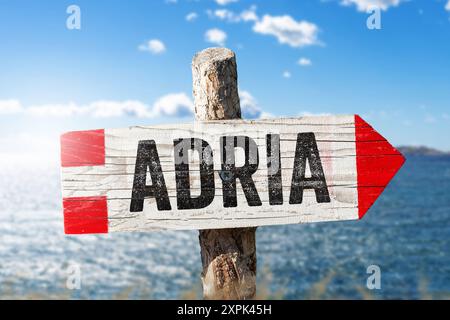 6 agosto 2024: Vacanza sull'insegna dell'Adriatico. Cartello in legno davanti al sole sul mare. Immagine del simbolo di destinazione. FOTOMONTAGGIO *** Urlaub an der Adria Schild. Wegweiser aus Holz vor Sonnenschein am Meer. Reiseziel Symbolbild. FOTOMONTAGE Foto Stock