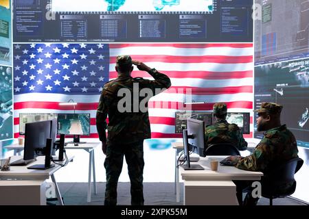 Personale militare americano che supervisiona l'attività di guerra informatica in un ufficio high-tech, esamina l'intelligence top secret sul grande schermo. Esperti governativi gestiscono la guerra ibrida, la prevenzione dei conflitti. Foto Stock