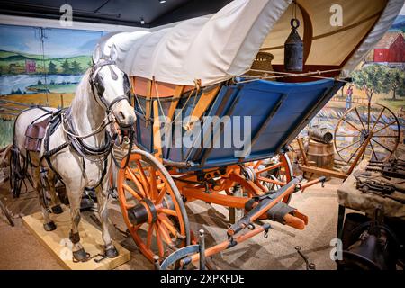 Virginia Freight Wagon Luray Virginia United States // LURAY, Virginia, Stati Uniti — un Virginia Freight Waggon del 1810, costruito a Newtown (ora Stephens City), Virginia, è in mostra al Luray Valley Museum. Questo tipo di carro, tipicamente trainato da una squadra di sei cavalli con campane, era cruciale per il trasporto di merci dalla valle dello Shenandoah a Baltimora, giocando un ruolo vitale nel commercio americano all'inizio del XIX secolo prima dell'avvento dei canali e delle ferrovie. Foto Stock