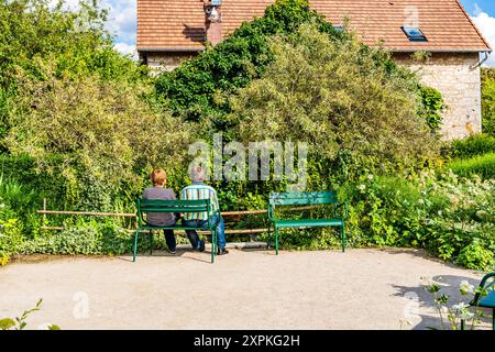 Una coppia seduta su una panchina nel colorato giardino del Musée des impressionnismes di Giverny, dove visse il pittore francese Claude Monet, in Normandia Foto Stock