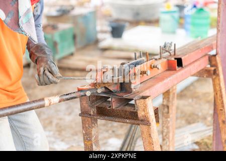 Il lavoratore sta piegando i tondini con deformazione patterns.in il cantiere. Foto Stock