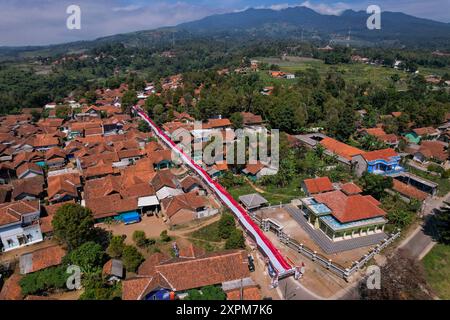 Majalengka, Giava occidentale, Indonesia. 7 agosto 2024. Vista aerea di un chilometro di stoffa rossa e bianca, come il colore della bandiera indonesiana, si vede nel villaggio di Lemahsugih a Majalengka, Giava occidentale. La comunità del villaggio di Lemahsugih ha decorato il proprio villaggio e ha diffuso un panno rosso e bianco come simbolo della bandiera indonesiana per accogliere il 79° giorno dell'indipendenza indonesiana, che cade il 17 agosto 2024. Crediti: ZUMA Press, Inc./Alamy Live News Foto Stock