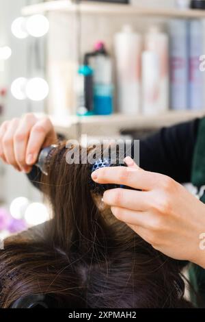 Primo piano di mani da parrucchiere e lunghi capelli marroni Foto Stock
