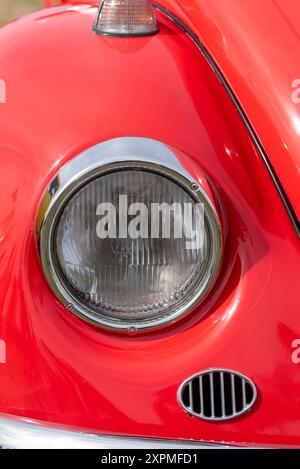 Faro anteriore su un'auto Volkswagen Beetle di colore rosso brillante. Agosto 2024. Foto Stock