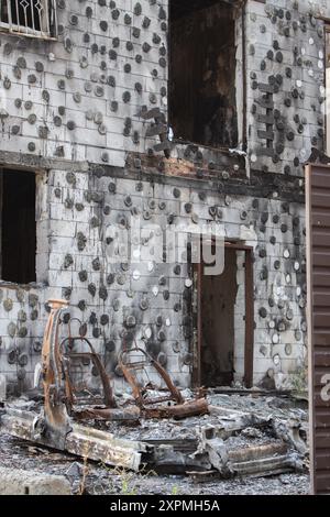 Casa bruciata e auto sul cortile. Edificio distrutto dopo l'invasione russa, Ucraina. Guerra in Ucraina. Abbandonato danneggiato casa e bruciato auto. Foto Stock