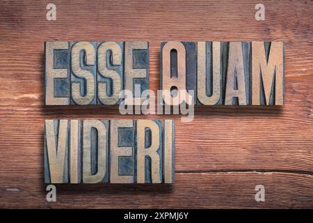 Essere piuttosto che sembrare (esse quam videri) frase latina combinata su una superficie in legno verniciato vintage Foto Stock