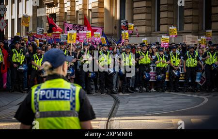 Gli agenti di polizia gestiscono grandi folle a Manchester durante una settimana di disordini nazionali. Gli agenti formano una linea di fronte ai contro-manifestanti anti-fascisti. Foto Stock