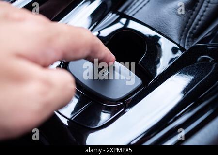 Premere a mano il pulsante del freno a mano elettronico in un'auto moderna di lusso Foto Stock