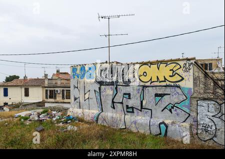 Arles, Francia - 7 marzo 2023: Muro con graffiti e spazzatura in giro, giorno nuvoloso in inverno Foto Stock
