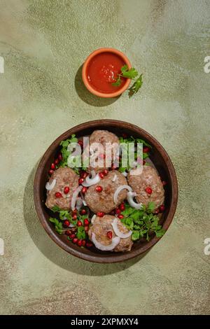 Composizione verticale con polpette di manzo o agnello fritte avvolte in grasso intestino e piccolo recipiente con salsa adjika Foto Stock