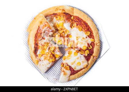 Una deliziosa pizza vegetariana al formaggio e al mais viene tagliata in quattro fette e una fetta di pizza viene morsa e posta sopra. Foto Stock