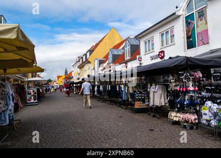 La principale strada pedonale nel centro di Skagen, Jutland settentrionale Danimarca, UE, con vestiti e scarpe in vendita su rotaie all'esterno dei negozi Foto Stock