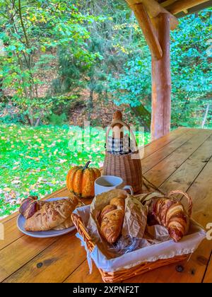 Accogliente mattina autunnale con dolci e caffè nella foresta su un tavolo di legno Foto Stock