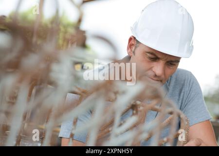 lavoratore maturo dietro le armature in cantiere Foto Stock