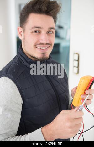 elettricista felice che lavora in sicurezza su interruttori e prese Foto Stock