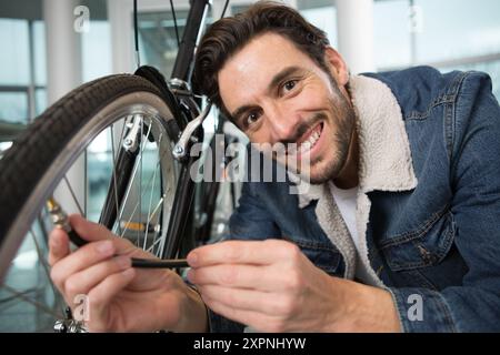 il giovane gonfia la ruota della bicicletta utilizzando una pompa Foto Stock