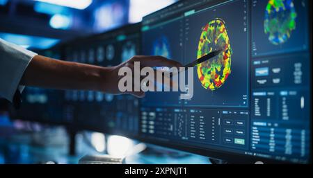 Modern Medical Research Center: Medico anonimo che punta al monitor di computer desktop con scansione TC del midollo spinale umano. Specialista in cerca di tumori o danni, in cerca di metodi di trattamento. Foto Stock