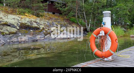 SOS concetto di emergenza nautica, salvagente messo su una stazione di ricarica per le barche con un mare sullo sfondo. Salvagente circolare presso il porticciolo dell'isola Foto Stock