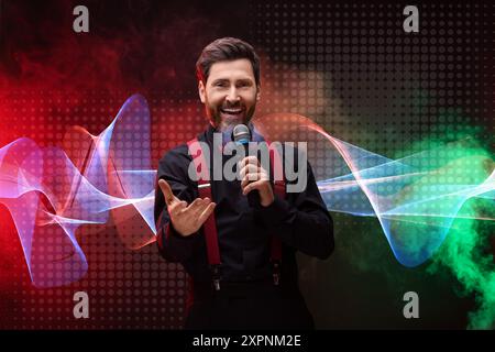 Uomo emotivo con microfono che canta nelle luci a colori. Forma d'onda audio vicino a lui Foto Stock