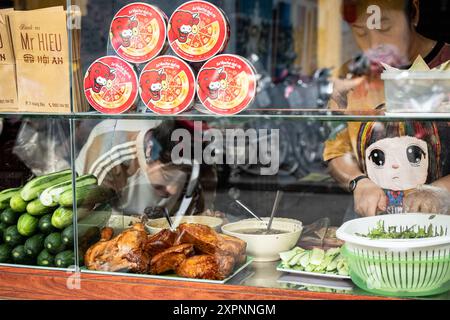 Chef di Street food che cucina in un venditore in un mercato di strada a Hoi An Vietnam. Venditore di alimenti che vende pollo alla griglia. Il cibo di strada è uno stile di vita in Asia-M. Foto Stock