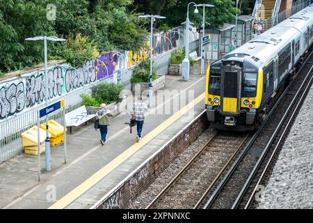 LONDRA - LUGLIO 2024: Passeggeri ferroviari che viaggiano sulla banchina di un treno sud-occidentale alla stazione di Barnes nel sud-ovest di Londra Foto Stock
