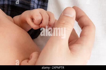 La mano del neonato tiene saldamente il dito di papà Foto Stock