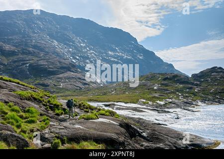 Un camminatore che passa il fiume Scavaig dove sfocia nel Loch na Cuilce, un'insenatura del Loch Scavaig., Isola di Skye, Scozia, Regno Unito. Sgùrr na Stri dietro. Foto Stock