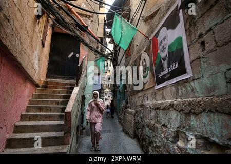 Beirut, Libano. 7 agosto 2024. Una ragazza palestinese passeggia accanto a un manifesto di Hamas che ha assassinato il leader Ismail Haniyeh in uno dei vicoli stretti del campo di Beirut Burj al-Barajneh. Crediti: Marwan Naamani/dpa/Alamy Live News Foto Stock