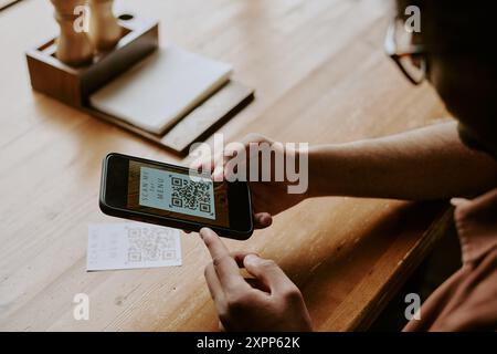 Scansione del codice QR con dispositivo smartphone su un tavolo in legno Foto Stock