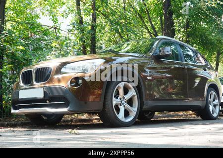 Bucarest, Romania - 21 luglio 2024: Vista frontale della BMW X5 SUV marrone parcheggiata vicino agli alberi Foto Stock