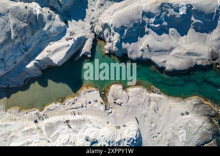 Veduta aerea della gente alla spiaggia di Sarakiniko con la sua roccia vulcanica bianca-grigia con baia e costa, Sarakiniko, Milos, Egeo meridionale, Grecia, Europa Foto Stock