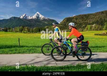 Uomo e donna in bicicletta sulla pista ciclabile del lago di Costanza-Königssee, Watzmann sullo sfondo, Bischofswiesen, alta Baviera, Baviera, Germania Foto Stock