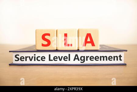 Simbolo SLA (Service Level Agreement). Parole concettuali SLA Service Level Agreement su bellissimi blocchi di legno e libro. Splendido sfondo bianco. Affari Foto Stock