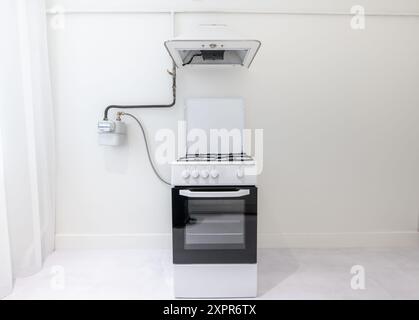 Interni luminosi in stile minimalista. Forno a gas, piano cottura. Muro bianco. Foto Stock