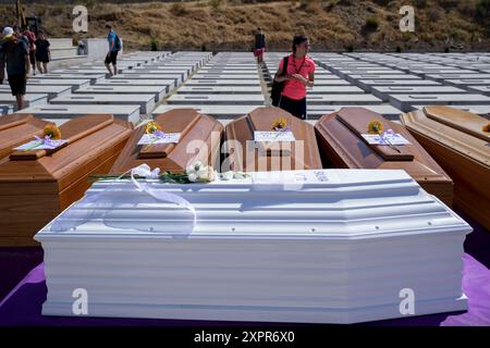 Reggio Calabria, Italia. 7 agosto 2024. Una ragazza vista davanti alla fila di bare. 21 migranti non identificati, morti nel naufragio del Mar Ionio lo scorso giugno, sono stati sepolti nel cimitero dei migranti di arma, Reggio Calabria. 11 migranti sono sopravvissuti al naufragio e sono stati portati a Roccella Jonica dalla Guardia Costiera Italiana, mentre almeno 36 corpi sono stati recuperati durante le operazioni di ricerca e soccorso e circa 20 persone sono scomparse. Foto Stock