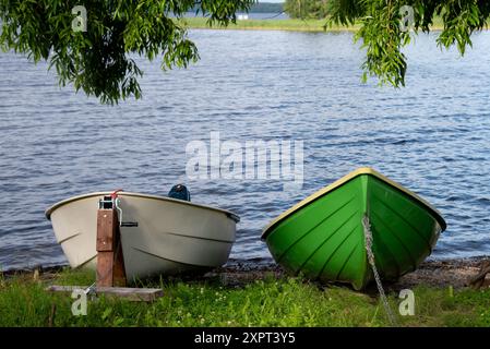 Barche a remi ormeggiate sul lago con acque calme Foto Stock