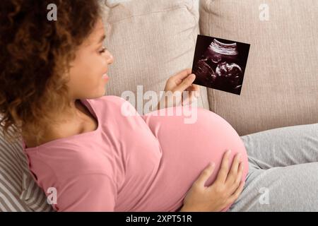 African-american donna incinta holding di scansione ad ultrasuoni a casa Foto Stock